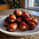 A tempting pile of freshly cooked, caramelized bacon-wrapped dates served on a white plate.