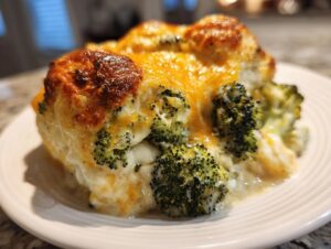 A close-up of a serving of creamy, cheesy Broccoli Casserole with a golden-brown, bubbly top.