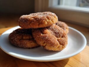 A stack of three chewy Snickerdoodle cookies heavily coated in cinnamon sugar, resting on a white plate.