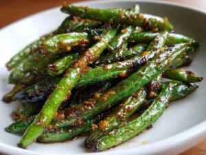 A close-up of vibrant green beans coated in a savory garlic sauce, ready to serve.