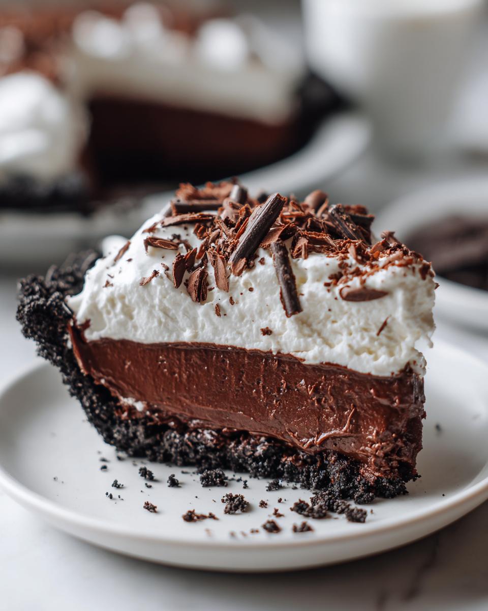 A decadent slice of Christmas chocolate cream pie featuring a dark crust, rich chocolate filling, and whipped cream topped with chocolate shavings.