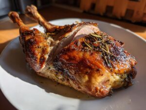 Close-up of a perfectly cooked roast duck portion showing crispy, golden-brown skin seasoned with rosemary.