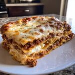 A thick, layered slice of Lasagna with Cottage Cheese, topped with melted, browned mozzarella and herbs.