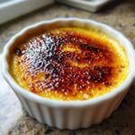 Close-up of a single serving of Creme Brulee with a deeply caramelized, crackling sugar crust.