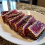 Slices of perfectly cooked Seared Ahi Tuna, showing a deep red center and a thick sesame seed crust.