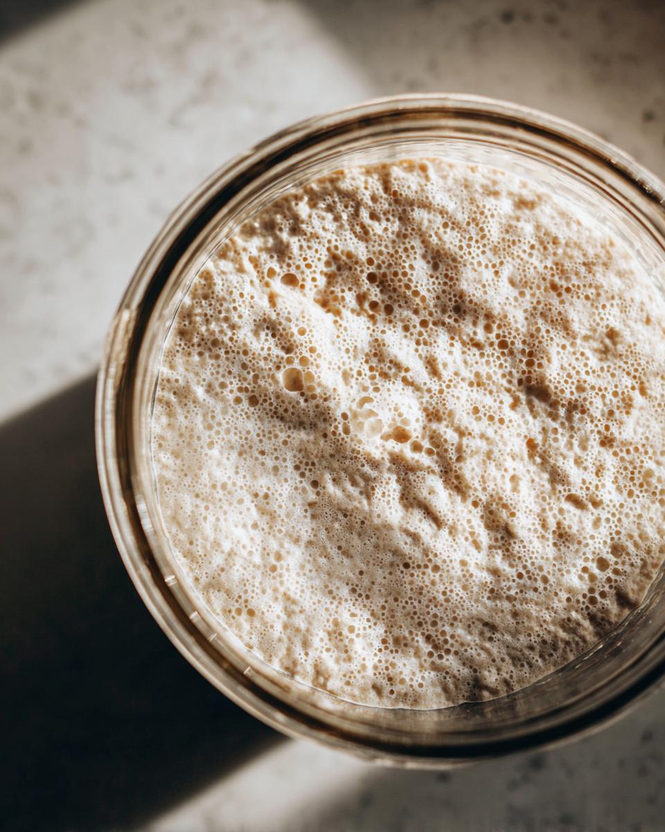 Overhead view of a highly active sourdough starter, showing a thick layer of small, uniform bubbles.