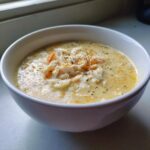 Close-up of a creamy, rich bowl of crab soup topped with shredded crab meat and herbs.