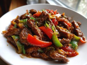 Close-up of amazing pepper steak strips coated in dark savory sauce with bright red and green bell peppers.