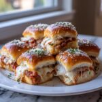 A pile of gooey, cheesy pizza sliders topped with Parmesan and parsley, ready to eat.