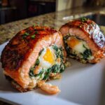 Cross-section of amazing stuffed salmon revealing a creamy spinach filling and a whole baked egg inside.