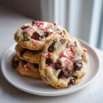 A stack of four chewy peppermint chocolate chip cookies loaded with dark chocolate chunks and crushed candy canes.