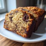 Close-up of three thick slices of moist chocolate chip banana bread recipe on a white plate.