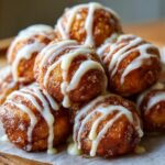 A tempting pile of golden brown cinnamon roll bites drizzled generously with white vanilla icing.