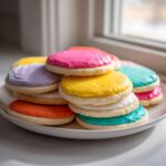 A stack of soft sugar cookies topped with brightly colored, smooth sugar cookie icing recipe frosting.