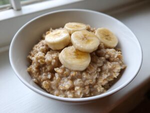 Close-up of a white bowl filled with creamy banana oatmeal, topped with four slices of fresh banana.