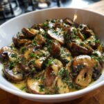 Close-up of sautéed brown mushrooms coated in a creamy, savory mushroom sauce and topped with fresh parsley.