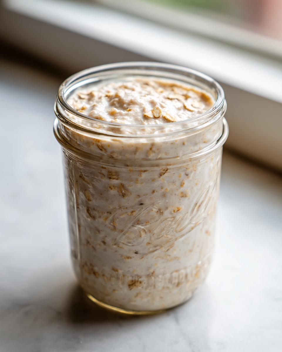Close-up of creamy overnight oats prepared in a clear glass mason jar, ready for breakfast.
