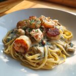 A close-up of creamy seafood pasta featuring linguine, seared scallops, shrimp, and crab meat, garnished with parsley.