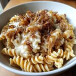 Close-up of creamy french onion pasta made with fusilli, topped generously with melted cheese and caramelized onions.