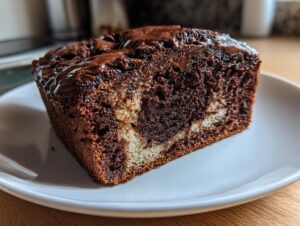 Close-up of a moist slice of hot fudge brownie bread showing a marbled interior and rich chocolate topping.