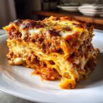 A thick, layered slice of cheesy instant pot lasagna with rich meat sauce on a white plate.