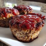 Close-up of three juicy mini meatloaf portions topped with a thick, shiny red glaze.