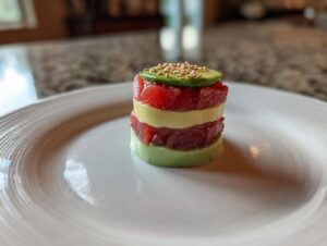 A perfectly layered tower of tuna tartare and avocado, topped with avocado and sesame seeds.