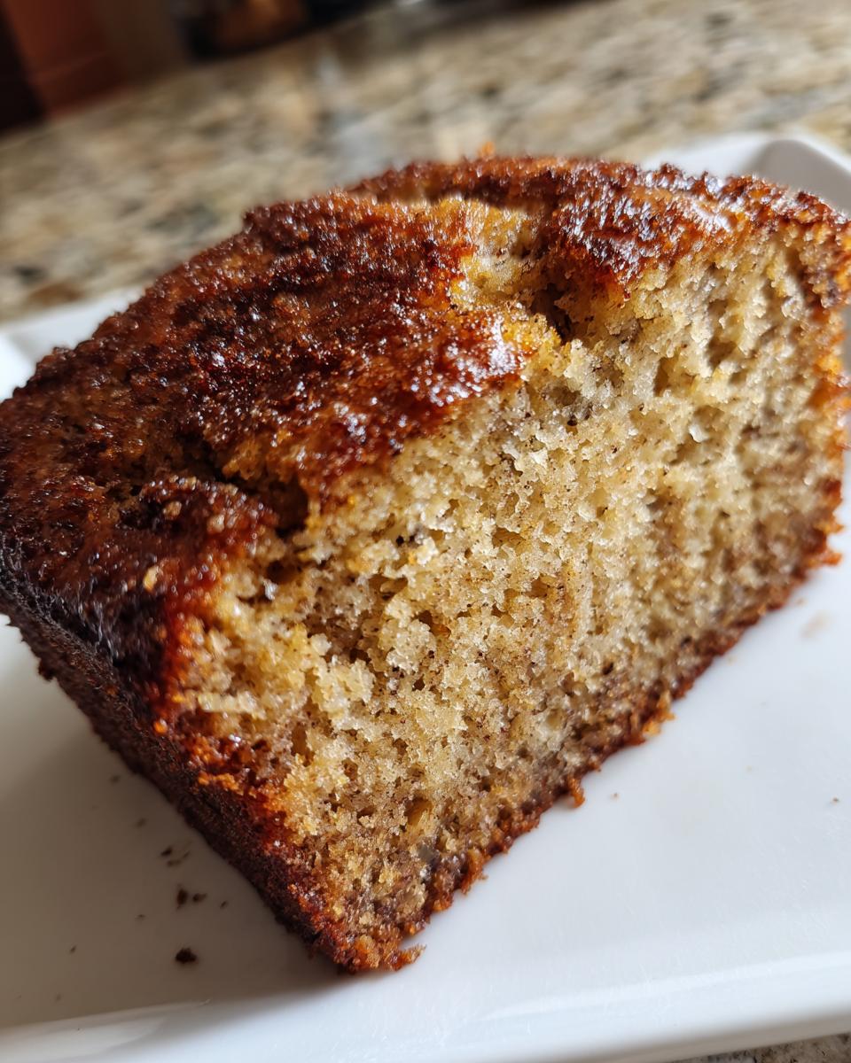 Close-up of a moist slice of greek yogurt banana bread showing the dense crumb and caramelized top.