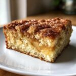 A close-up of a moist slice of jewish apple cake showing tender crumb and cinnamon apple filling.
