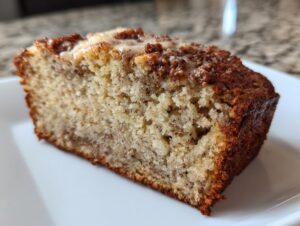 Close-up of a moist slice of greek yogurt banana bread with a cinnamon swirl and light glaze.