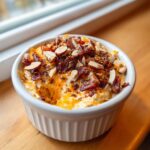 A small white ramekin filled with creamy Neiman Marcus Dip, topped generously with bacon bits and sliced almonds.