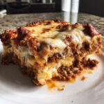 Close-up of a gooey, cheesy slice of sheet pan lasagna with rich meat sauce.