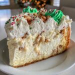A close-up slice of Christmas tree cheesecake with a thick, creamy filling, graham cracker crust, and festive whipped cream topping.