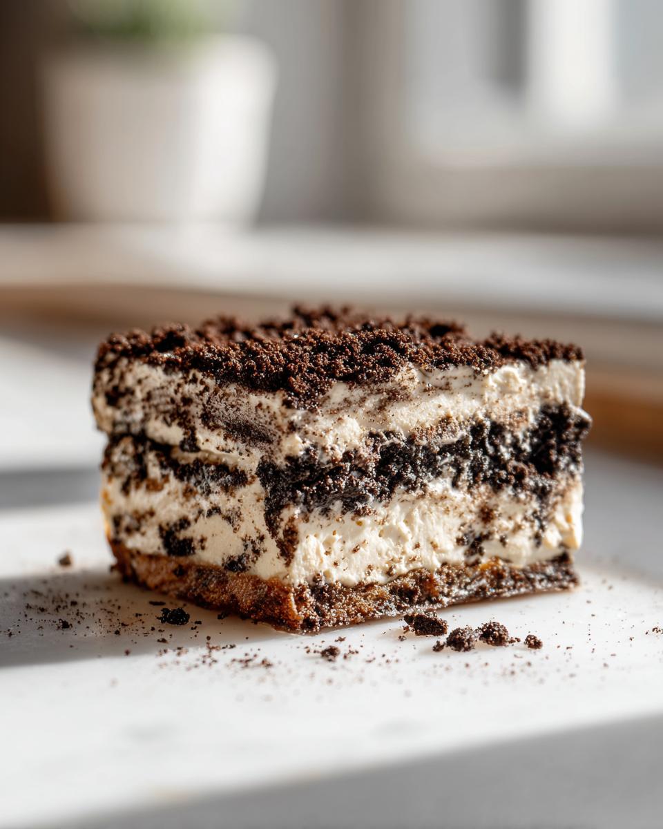 Close-up of a decadent slice of layered Oreo dirt cake showing cream filling and crushed cookies.