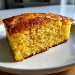 Close-up of a moist, golden slice of skillet cornbread showing its crumb texture and dark, caramelized crust.