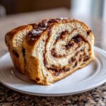 Two thick slices of homemade raisin bread showing a rich swirl of cinnamon and plump raisins.