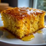 Close-up of a square slice of moist, golden sweet potato cornbread drizzled generously with honey.
