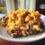 A close-up serving of cheeseburger casserole featuring elbow macaroni, ground beef, green peppers, and melted cheddar cheese.