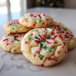 A stack of soft, chewy Christmas sprinkle sugar cookies topped with red, green, and white holiday sprinkles.