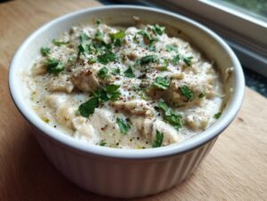A close-up of a serving of creamy white chicken chili, topped with fresh parsley and cracked black pepper.