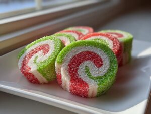 Close-up of several brightly colored red, white, and green pinwheel cookies coated in sugar.