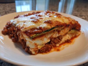 A thick, firm slice of zucchini lasagna layered with meat sauce, ricotta, and topped with melted, browned cheese.