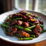 Close-up of saucy, glazed chicken pieces mixed with vibrant green beans, a perfect chicken and green beans dinner.