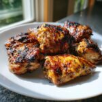 A plate of perfectly grilled chicken pieces showing charred edges, likely prepared with a flavorful chicken marinade.