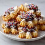 A pile of golden Italian butter cookies dipped in chocolate and covered with colorful sprinkles.