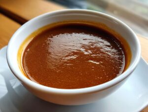 Close-up of rich, thick homemade brown gravy served in a small white bowl.