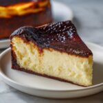 Close-up of a perfect slice of Basque burnt cheesecake showing the creamy interior and dark caramelized top.