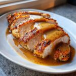 Slices of juicy slow cooker turkey breast with a crispy, seasoned edge, covered in savory brown gravy.