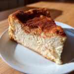 A close-up, sunlit slice of creamy snickerdoodle cheesecake topped generously with cinnamon sugar.