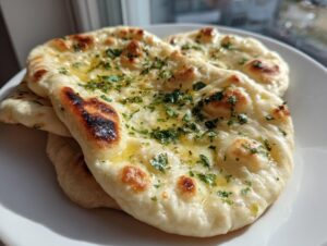 Close-up of freshly made, soft naan bread recipe brushed with melted butter and sprinkled with fresh parsley.